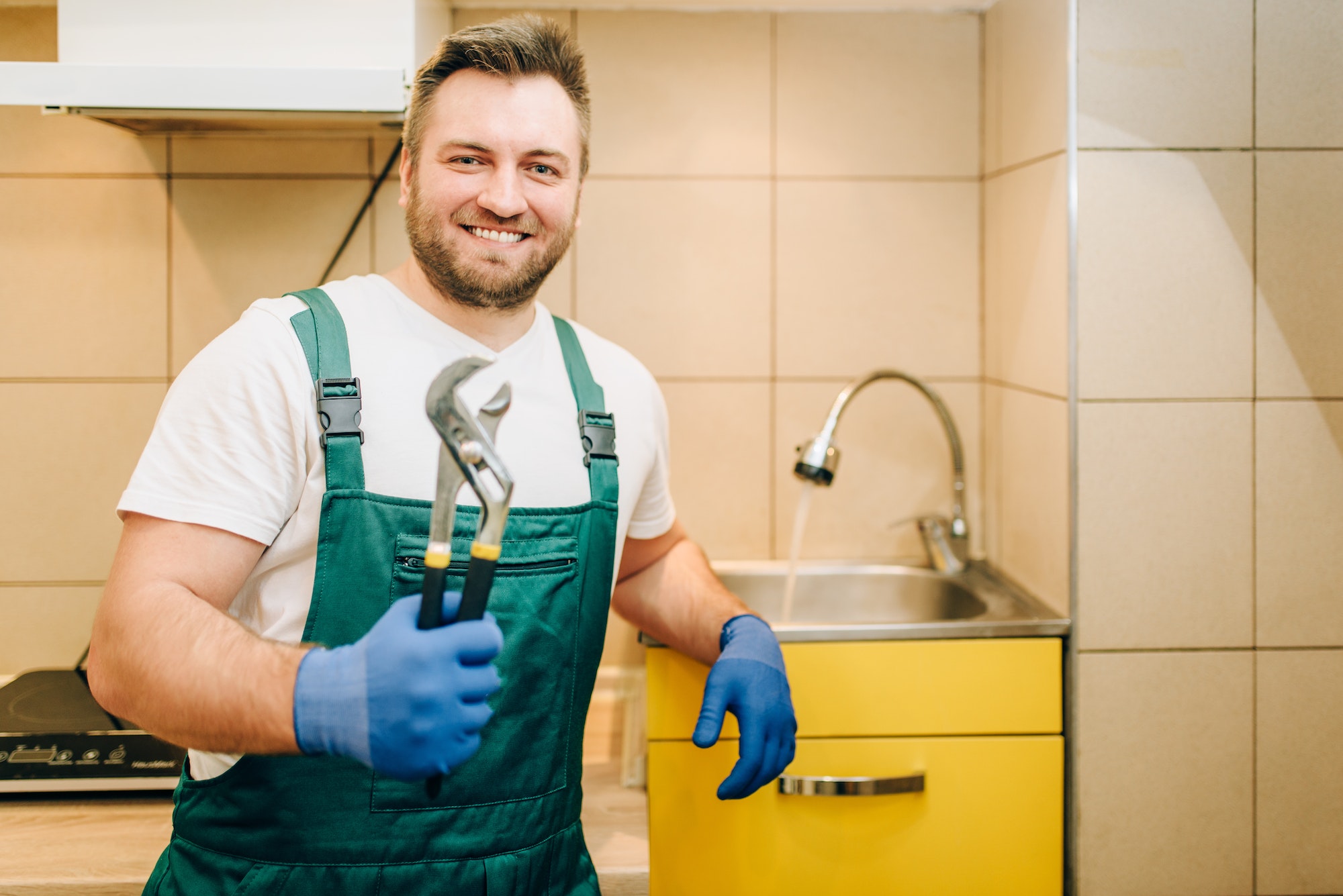 Plumber in uniform holds wrench, handyman